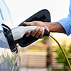 une personne branche une prise de recharge &agrave; sa voiture &eacute;lectrique